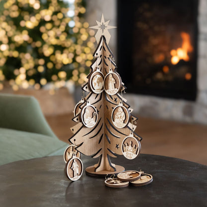 A wooden Christmas tree ornament display with carved profile figures and star details, set on a dark table in front of a blurred fireplace and festive lights.