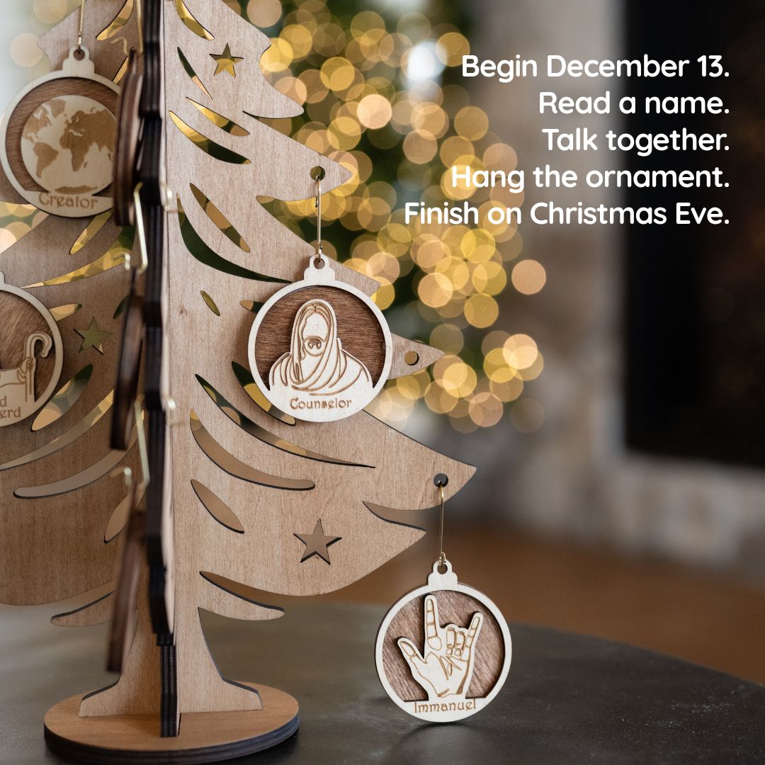 Personalized wooden Christmas ornaments hanging on a laser-cut wooden tree display, with a blurred holiday background and text on the right explaining the holiday name game activity.