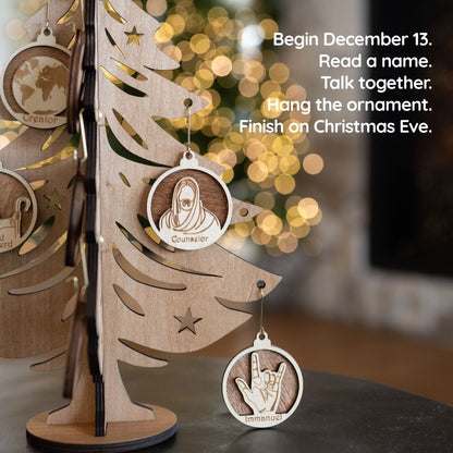 Personalized wooden Christmas ornaments hanging on a laser-cut wooden tree display, with a blurred holiday background and text on the right explaining the holiday name game activity.