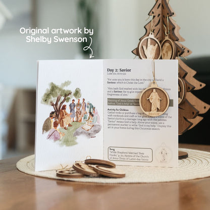 An open wooden Advent calendar card on a tabletop, showing printed text and illustrations, with a small wooden hanging ornament in front. A larger wooden tree decoration stands behind it, and the text 'Original artwork by Shelby Swenson' appears at the upper left.